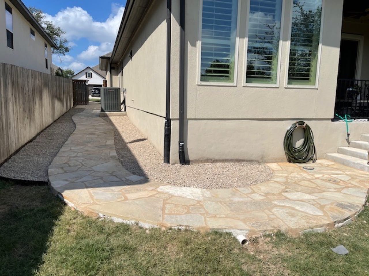 Flagstone walkway curving around the corner of a stucco house in Central Texas