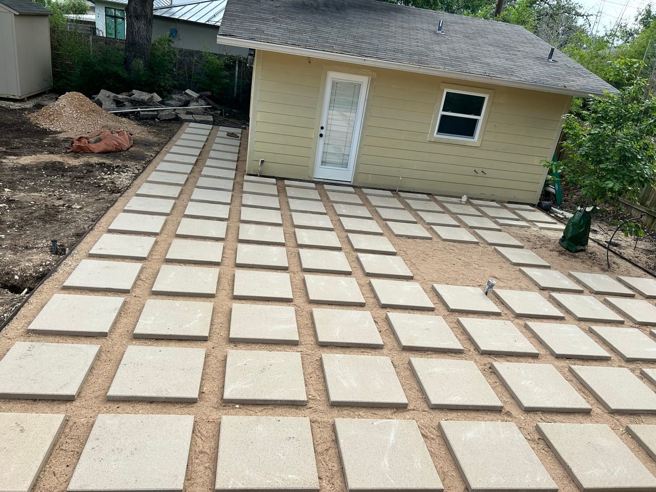 Large concrete paver grid patio with gravel joints behind a house in Austin, TX
