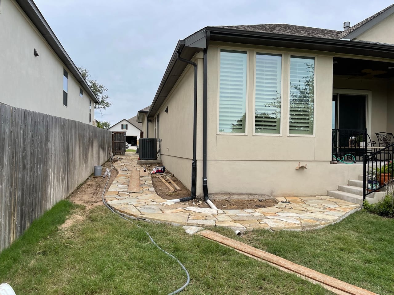 Narrow side yard stripped to dirt with flagstone work just starting by Corral Bros in Central Texas