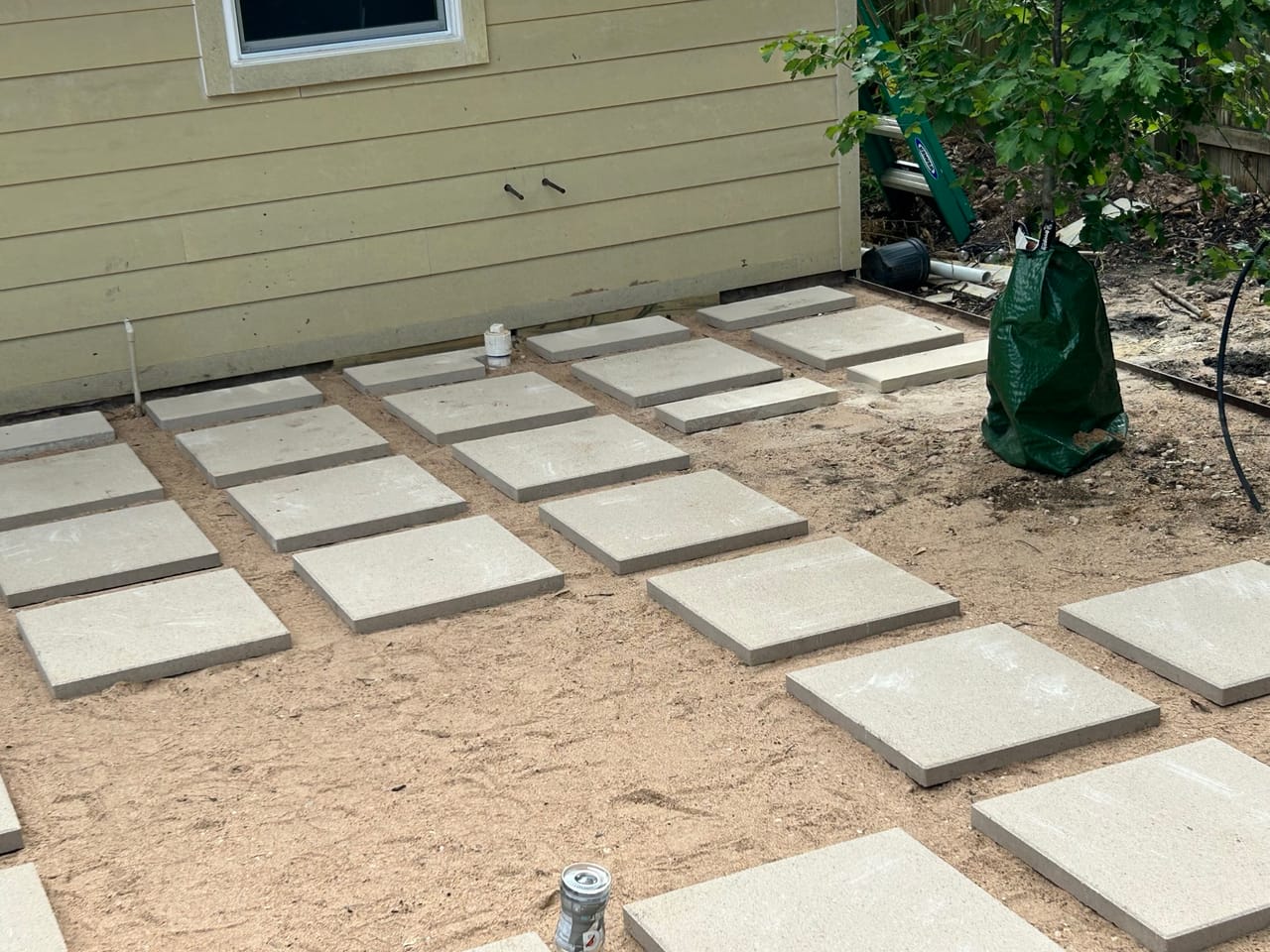 Paver grid patio being set in sand beside the house wall by Corral Bros in Central Texas