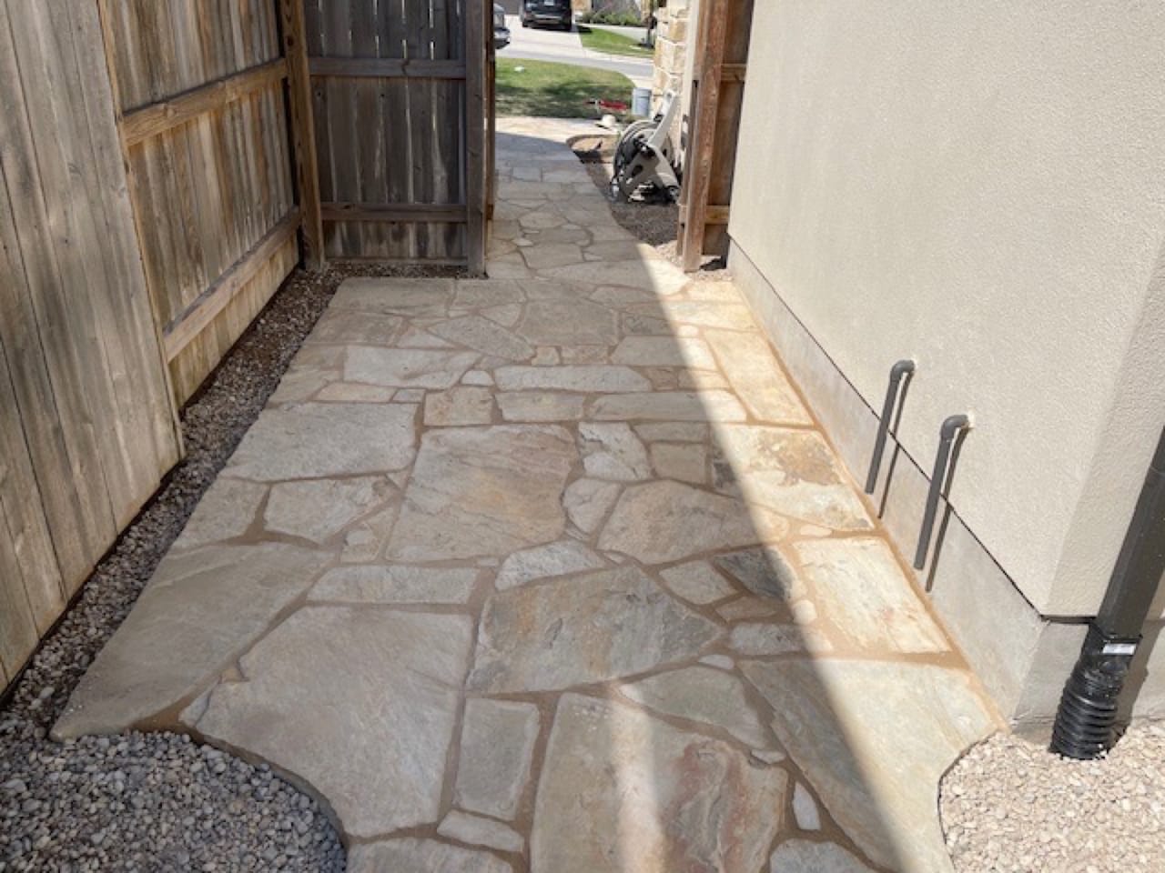 Wide flagstone landing set between cedar fence and stucco wall in Taylor, TX