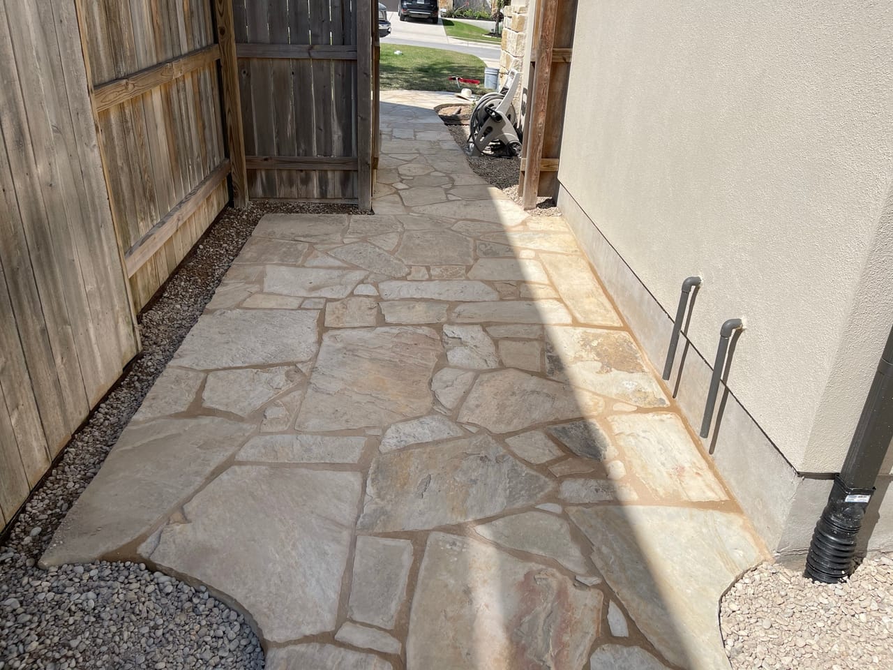 Wide flagstone path with gravel edging between fence and house wall in Central Texas