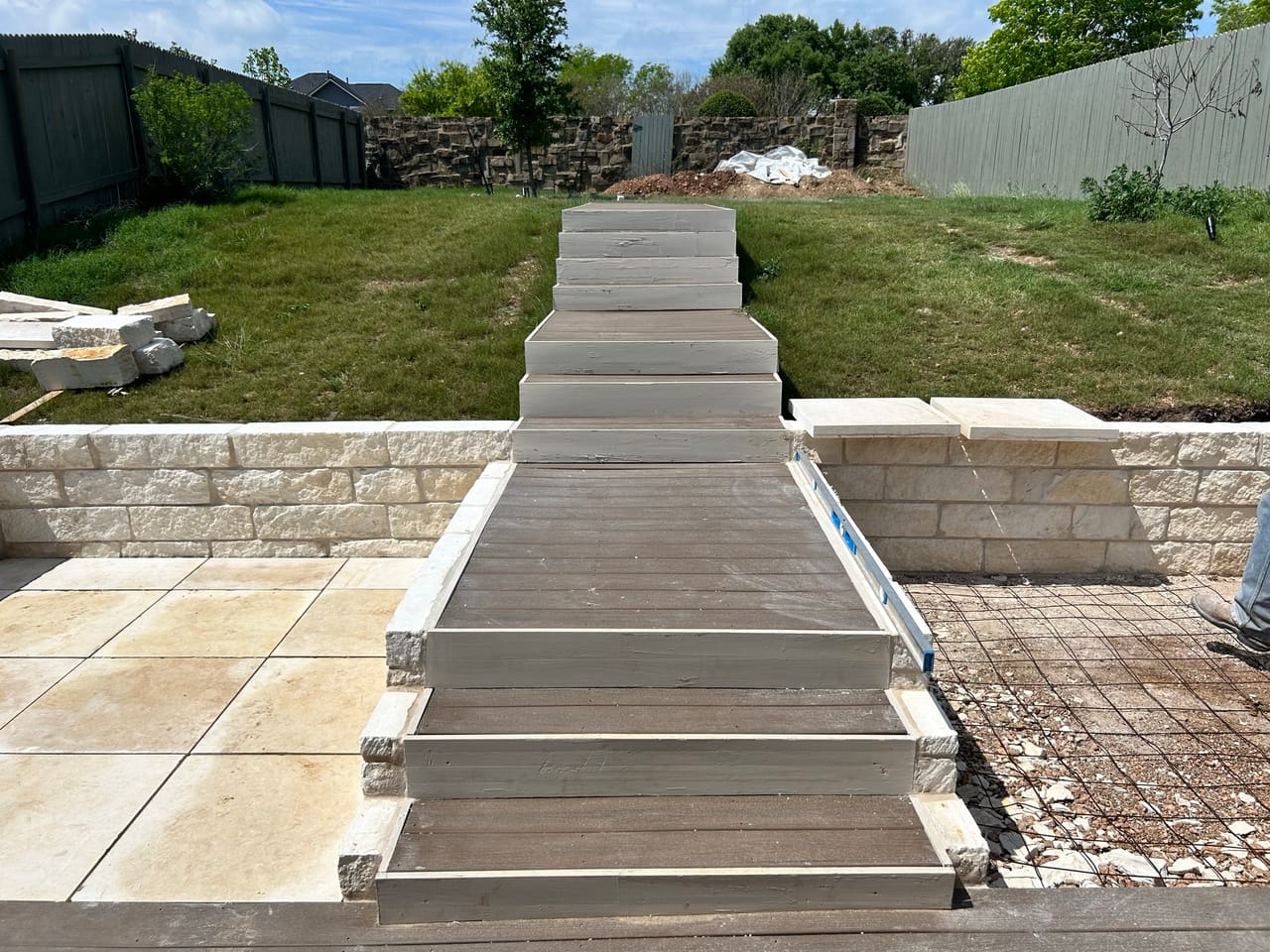Wide limestone steps between retaining walls leading to a paver patio in New Braunfels, TX
