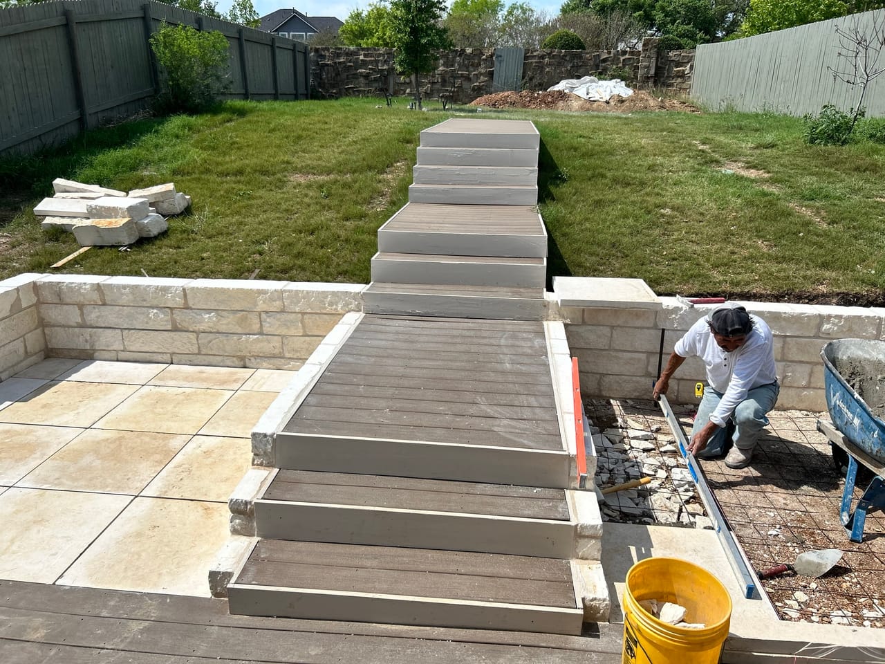 Worker finishing wide stone steps leading up from a new paver patio in Buda, TX