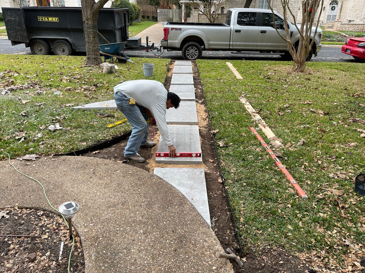 Worker leveling concrete pavers for a new front walkway by Corral Bros in Central Texas