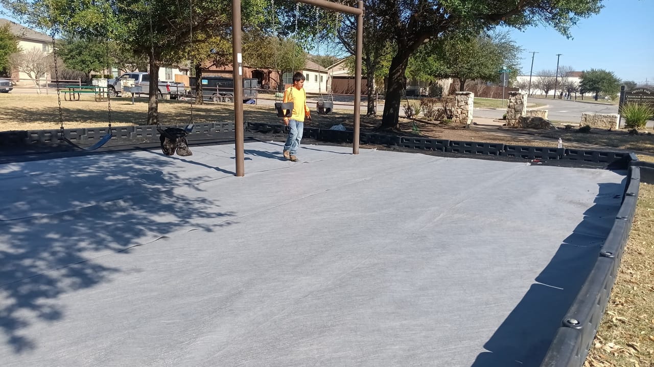 Worker standing on freshly poured concrete slab with new wood posts by Corral Bros in Central Texas