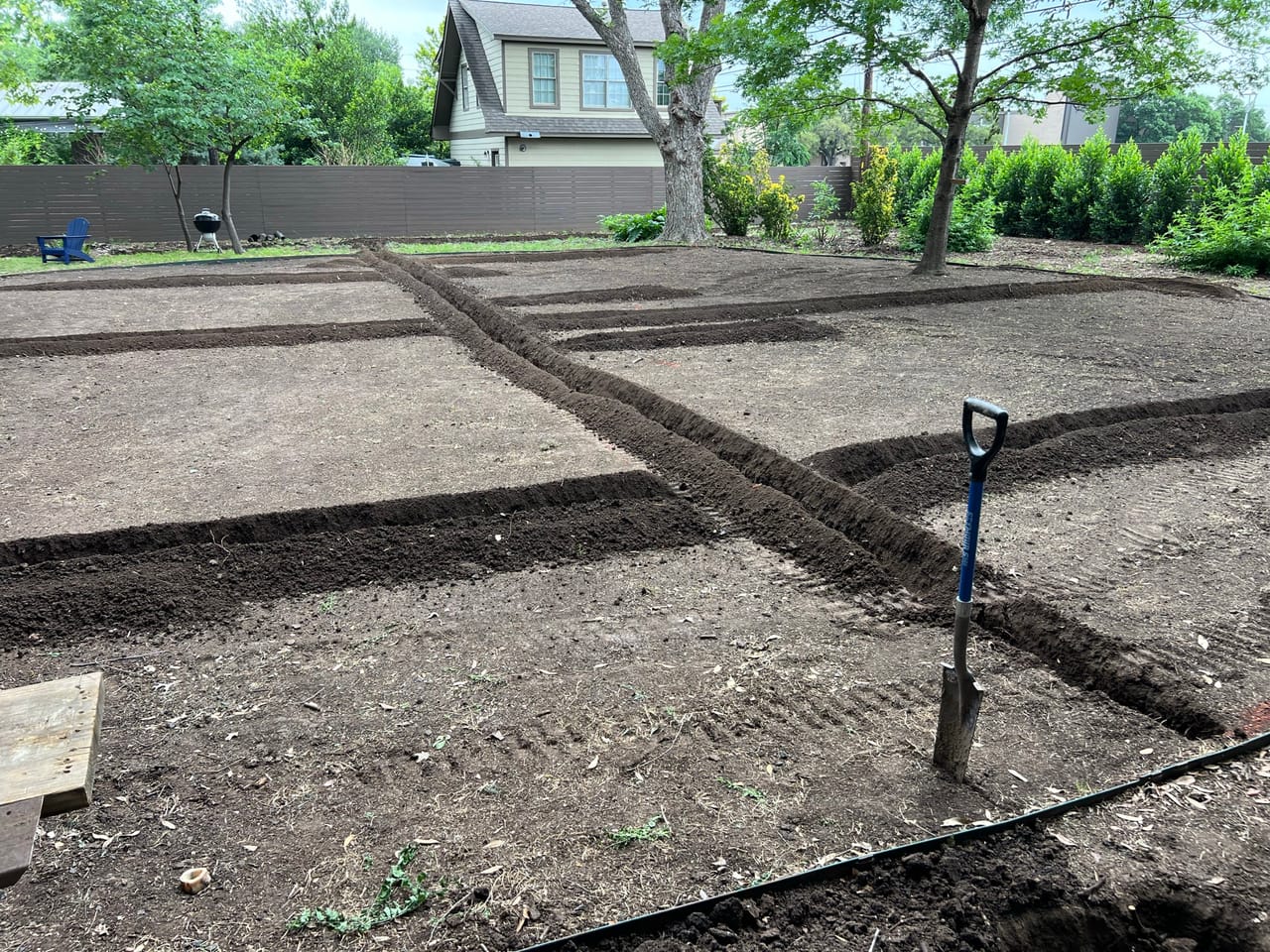 Grid of irrigation trenches cut across a bare backyard in Pflugerville, TX
