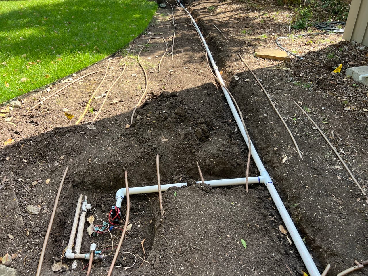Irrigation manifold and PVC lines in a trench beside lawn in Cedar Park, TX