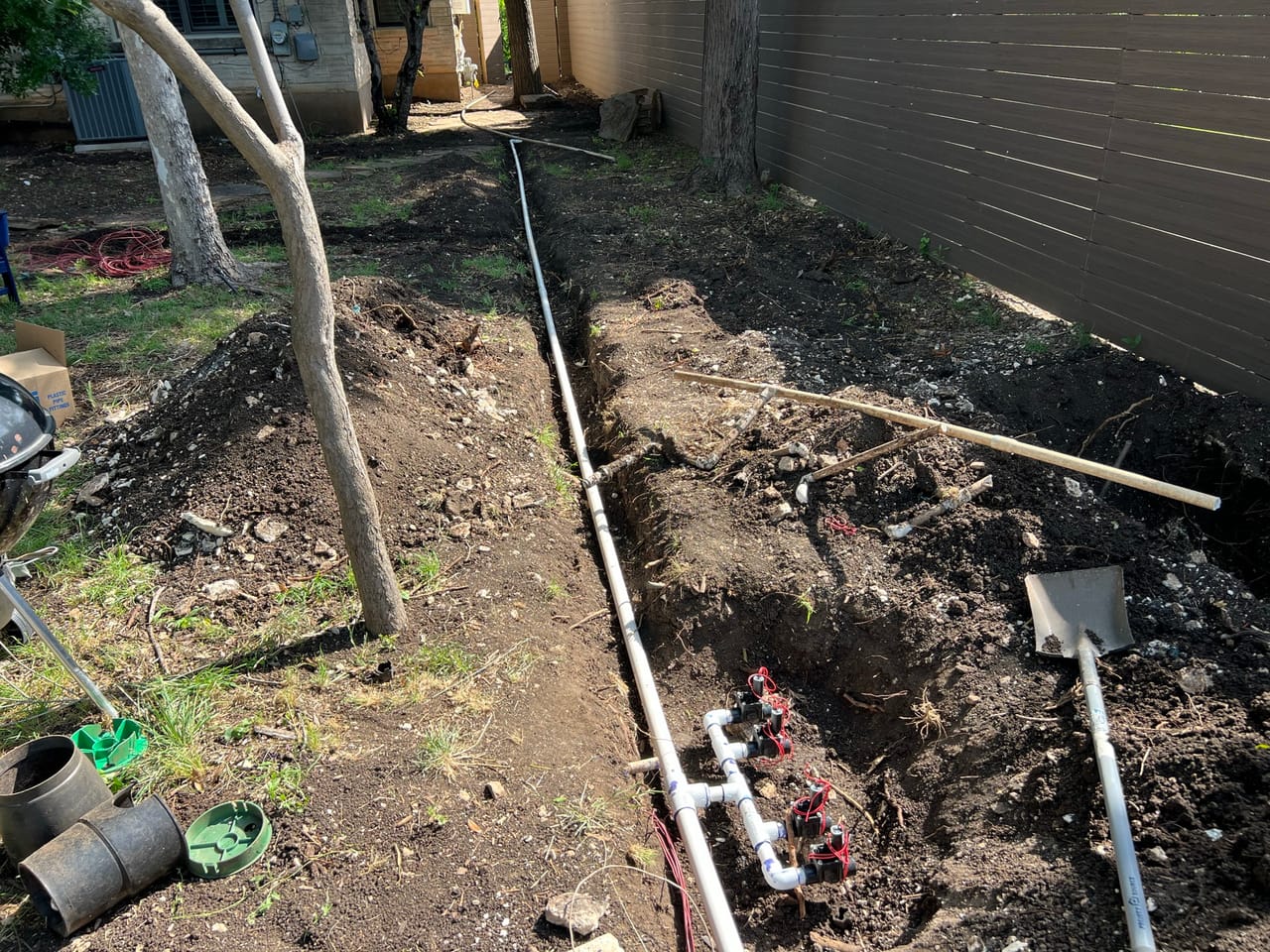 Irrigation pipe and valves in a trench along a fence in Leander, TX