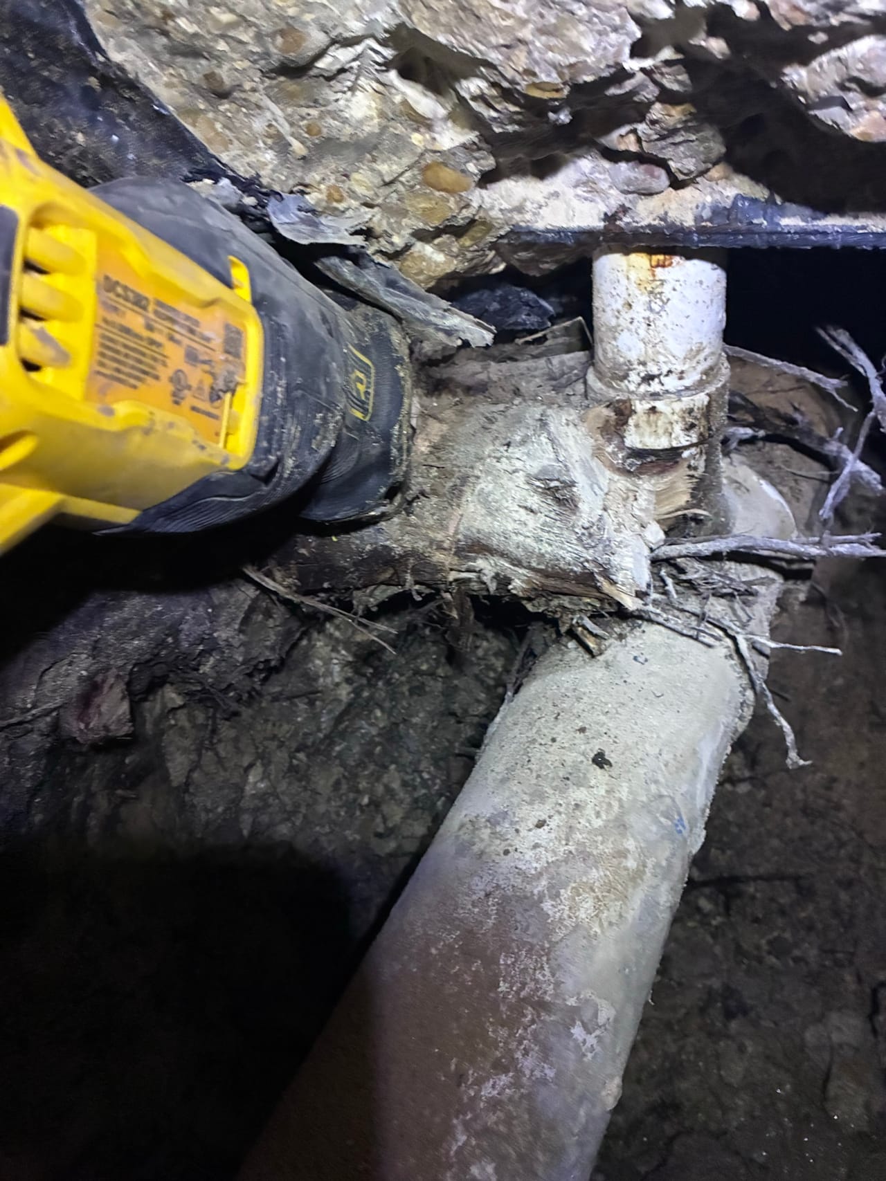 Reciprocating saw cutting a PVC water line in a rock trench in Buda, TX