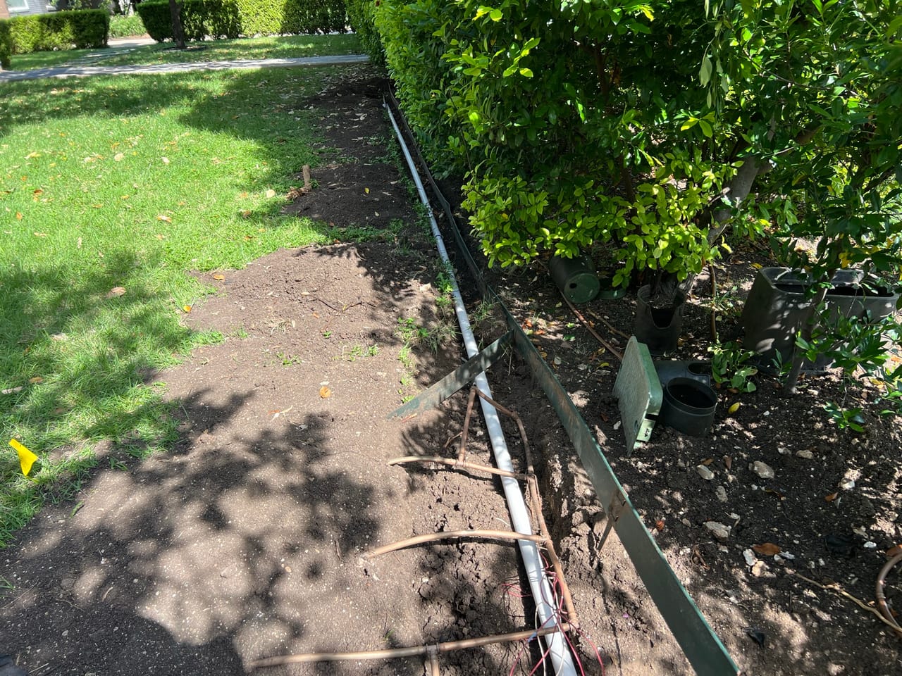 Irrigation trench following steel edging through a shaded lawn in Central Texas