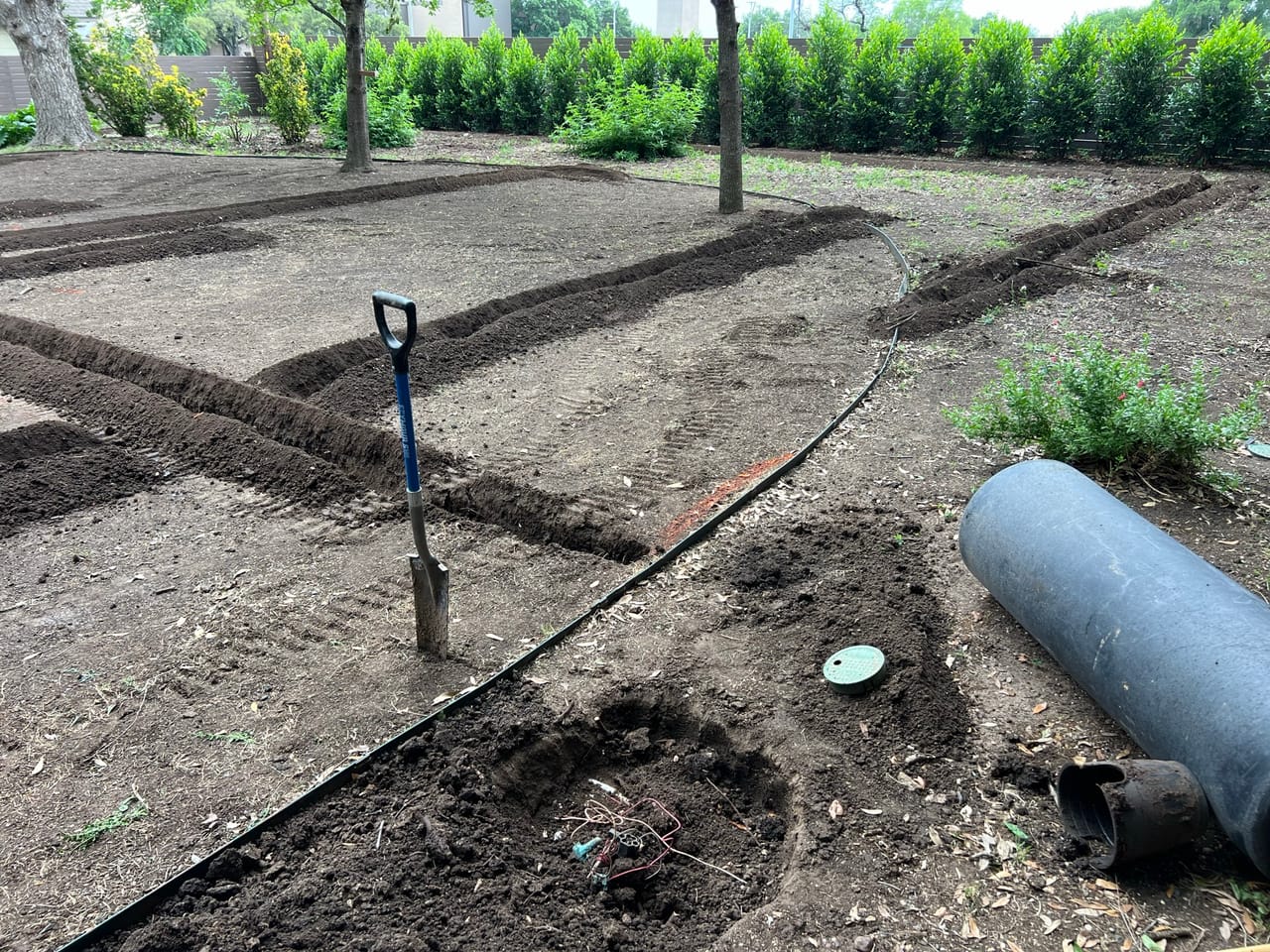 Trenched irrigation lines crossing a dirt yard with shovel standing in Georgetown, TX