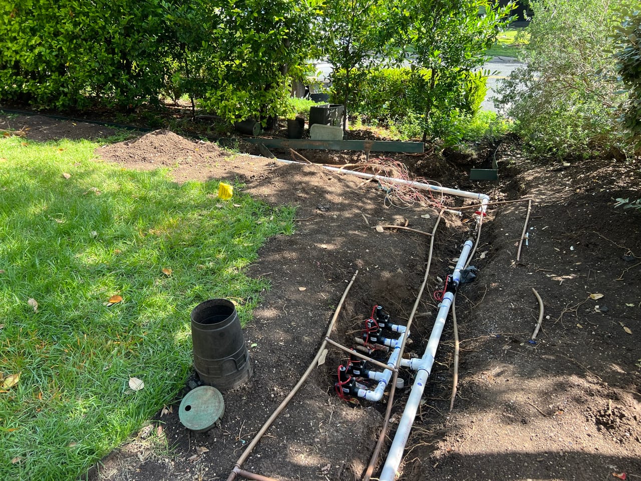 Irrigation valve manifold and PVC lines laid in an open trench in Georgetown, TX