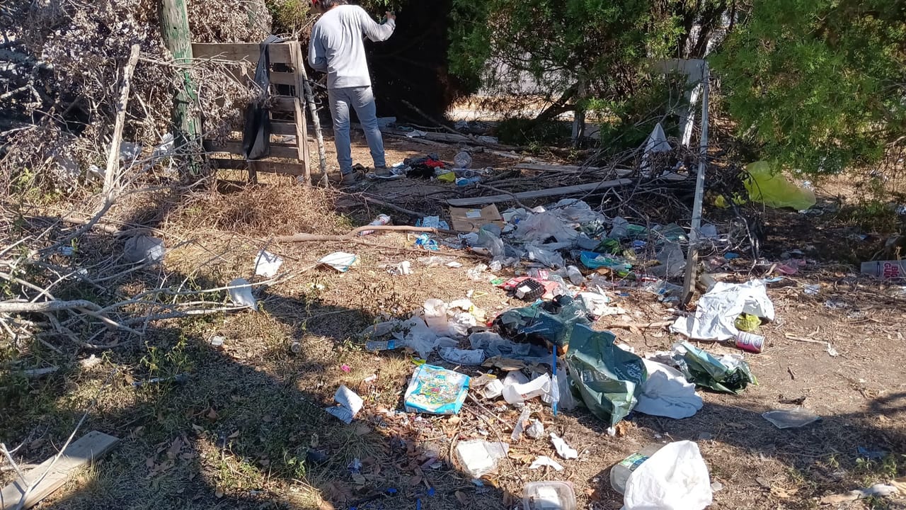 Worker clearing scattered trash and debris along an old fence line in Kyle, TX