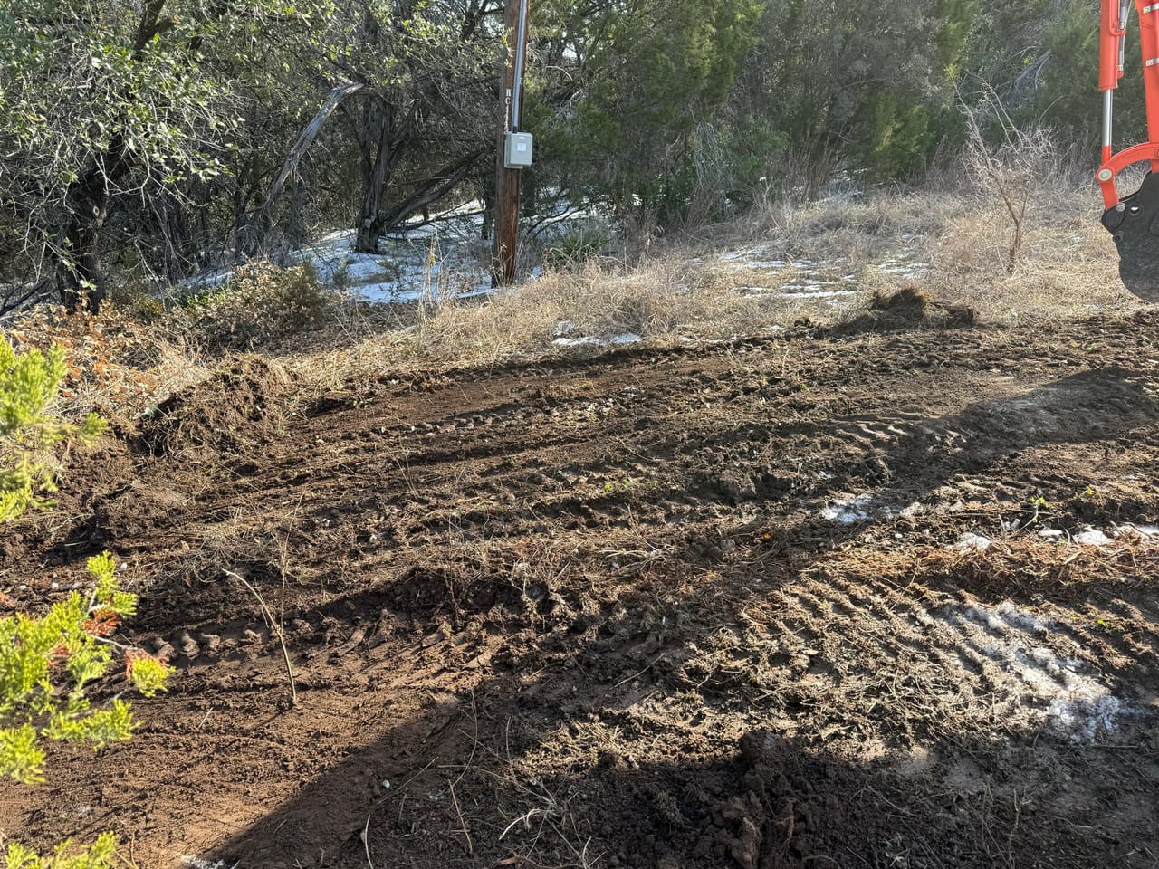 Cleared lot with turned soil and fresh excavator track marks in Kyle, TX