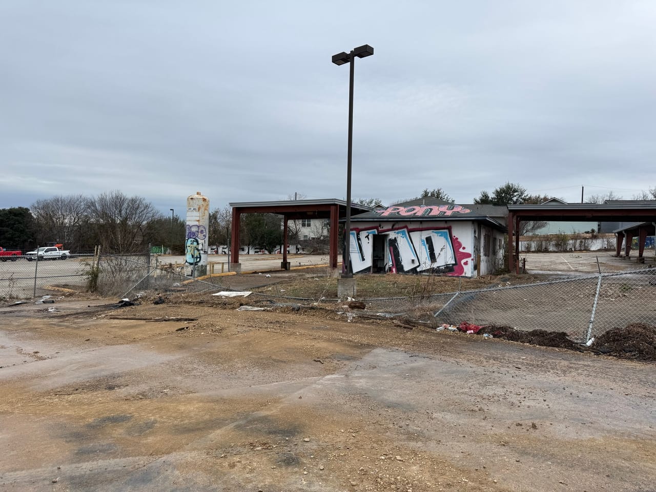 Graded dirt lot with graffiti tagged pavilion buildings in background in Central Texas