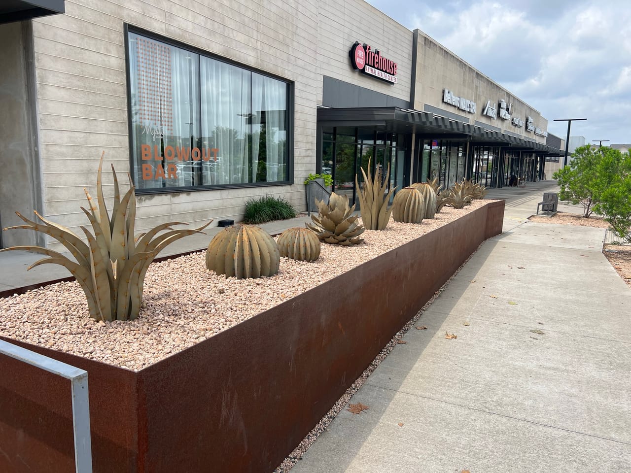 Corten planter with agave and barrel sculptures fronting a shopping center in Round Rock, TX