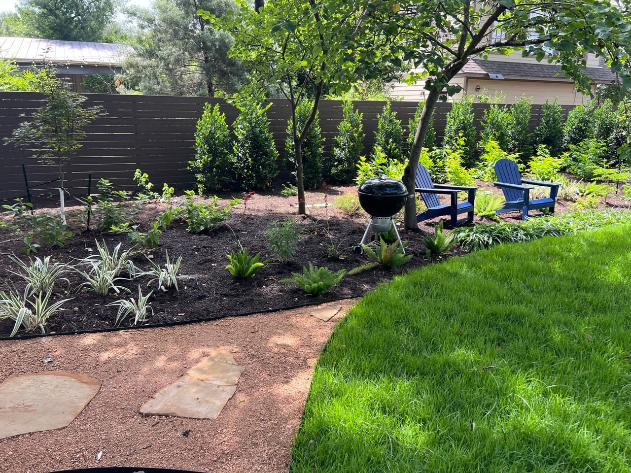 Curved mulch bed with new plants, chairs and stone path in Kyle, TX