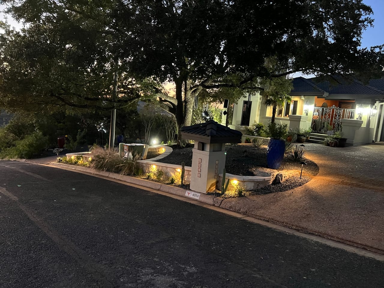 Dusk shot of commercial entry beds with landscape lighting and granite paths in Leander, TX