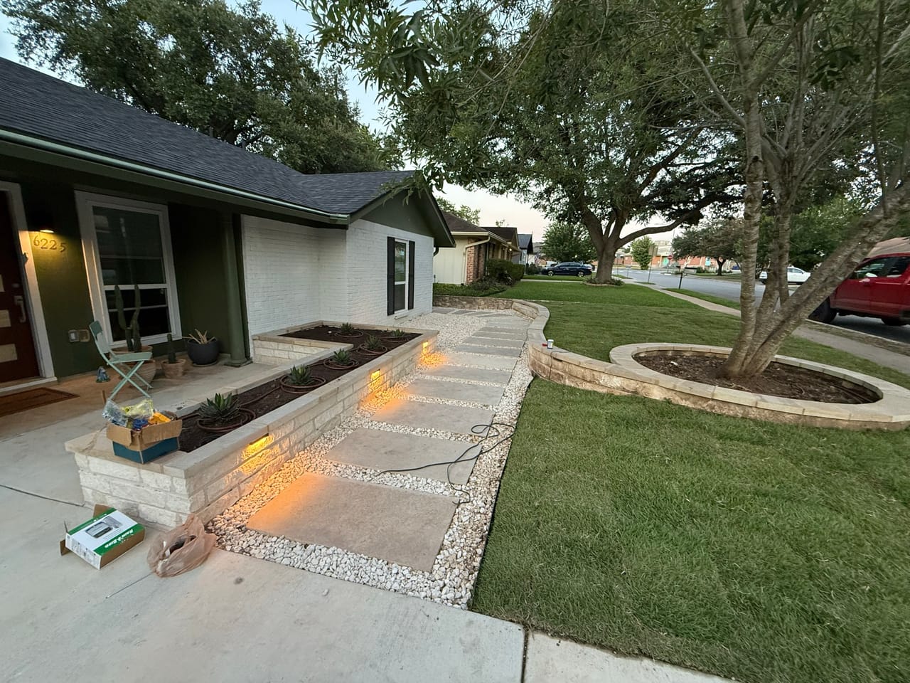 Evening front yard with lit stone walkway, lawn and planting beds in Lago Vista, TX