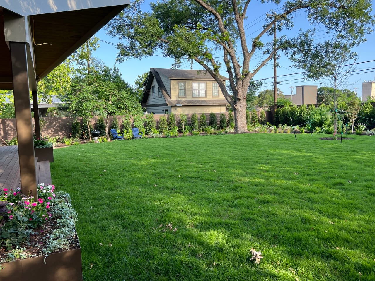 Green lawn and flower bed seen from under a covered patio in Buda, TX