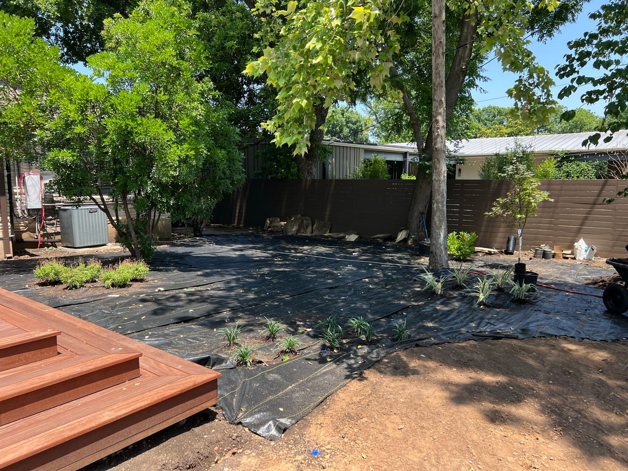 New deck steps with landscape fabric beds and young plants going in in Taylor, TX