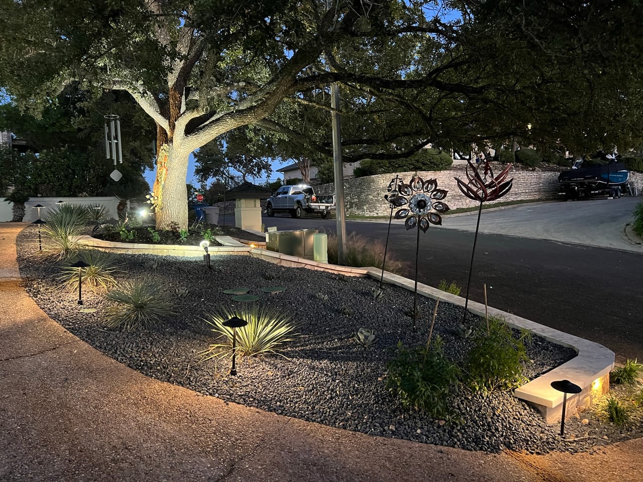 Uplit heritage oak over a curved planting bed with path lights in Georgetown, TX