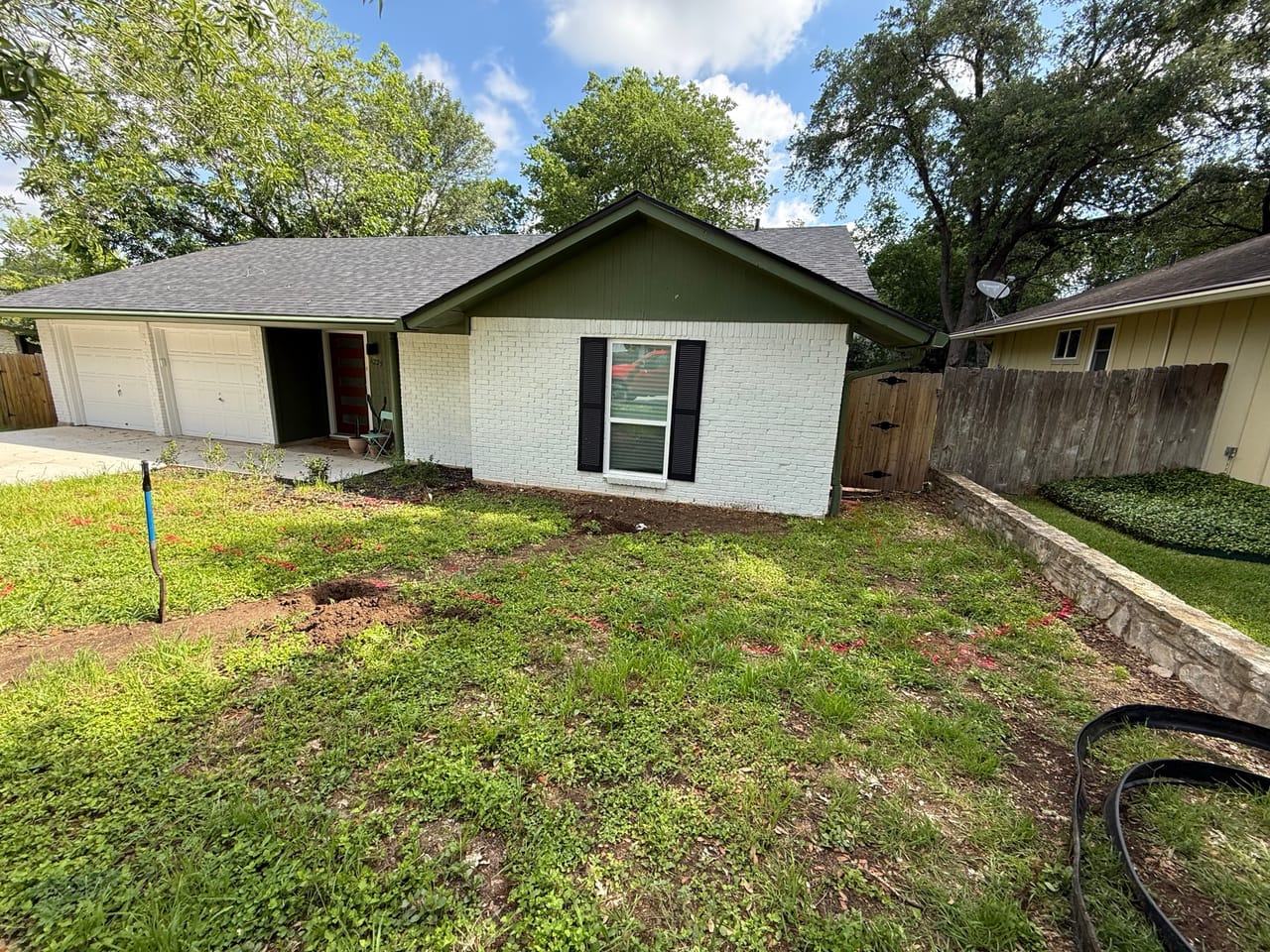 Backyard lawn behind a ranch house with hose across the grass in Taylor, TX