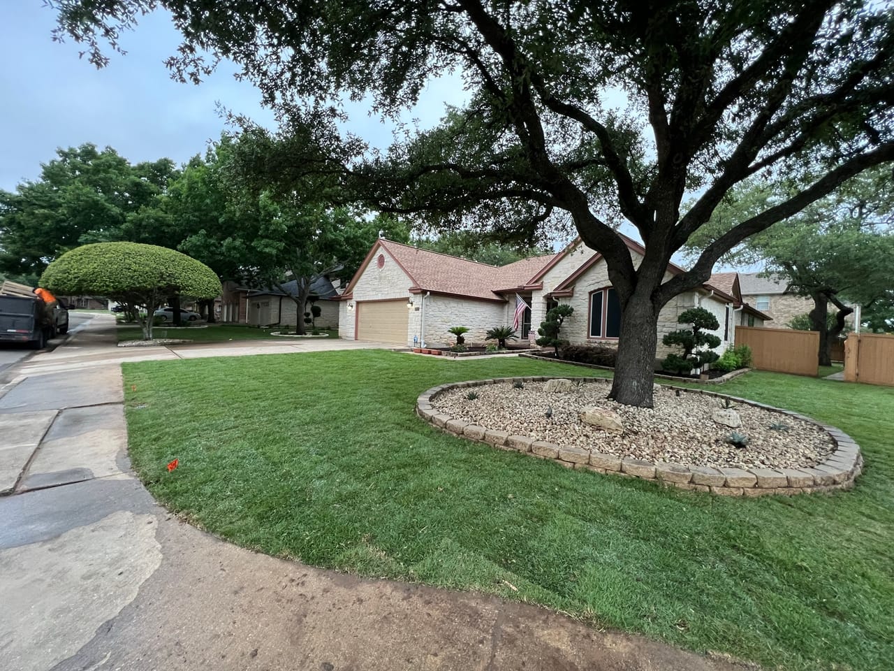 Groomed front yard with big oak, rock tree ring and shaped shrubs in Central Texas