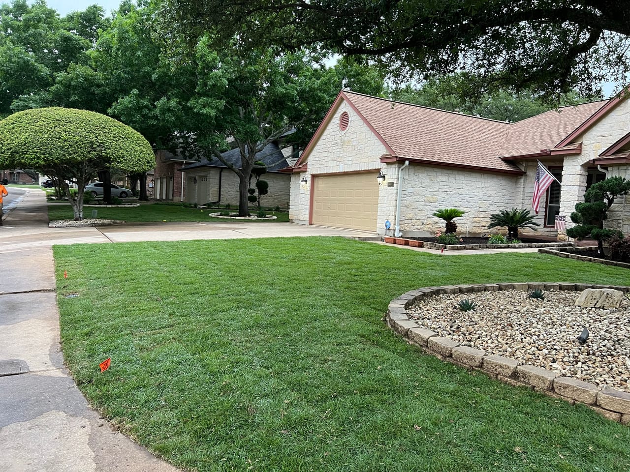 Tidy front yard with sculpted shrubs and a rock planting bed in Pflugerville, TX