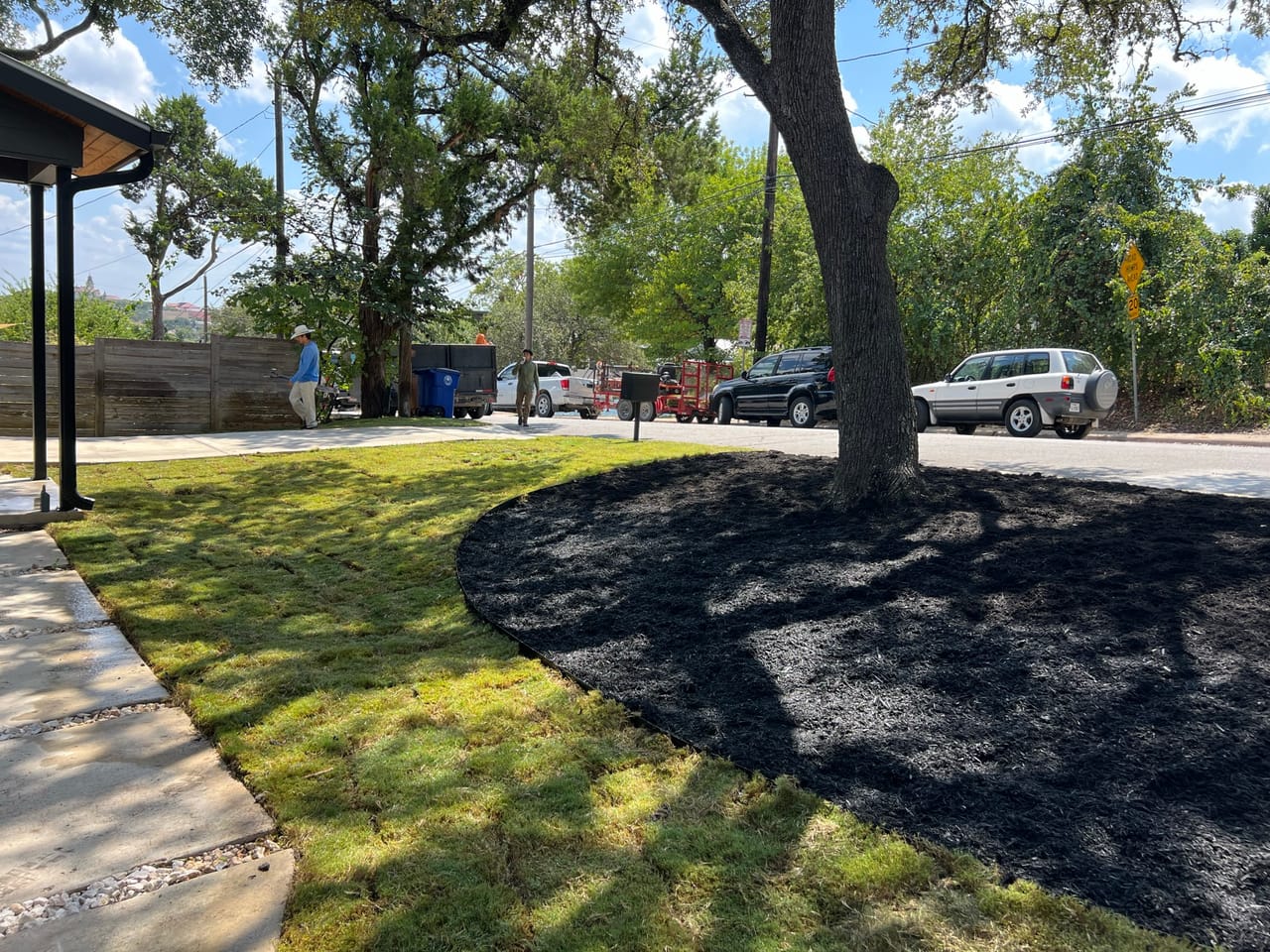 Black mulch ring installed around a tree in a green lawn in Wimberley, TX