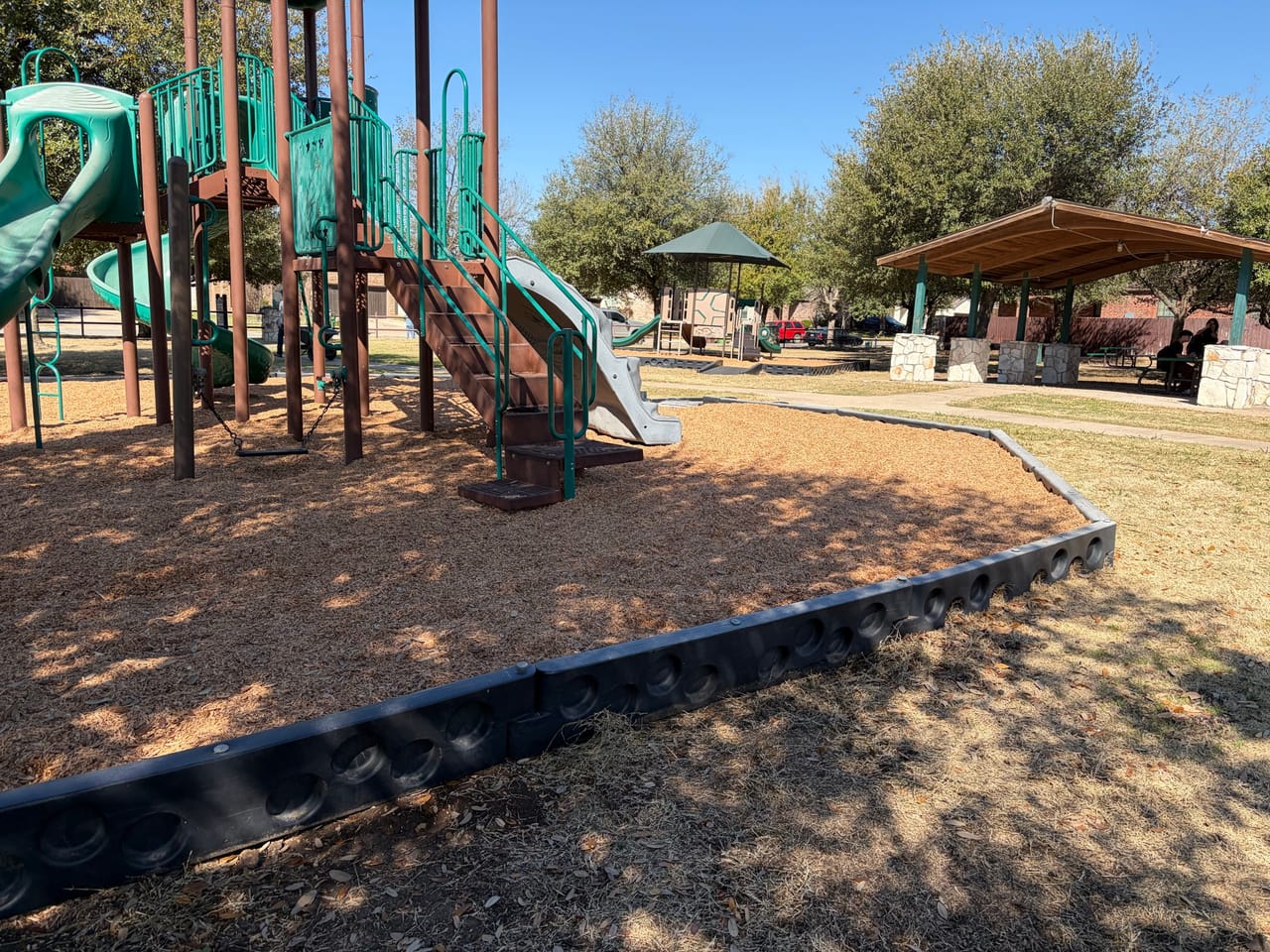 Clean playground with new mulch bed and crisp black border in Round Rock, TX