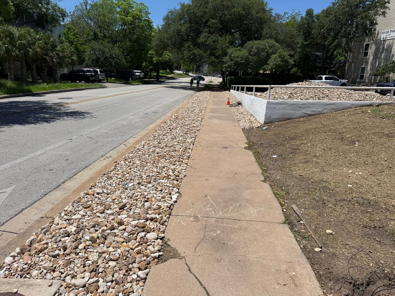 Clean river rock border running along a sidewalk and street edge in Pflugerville, TX