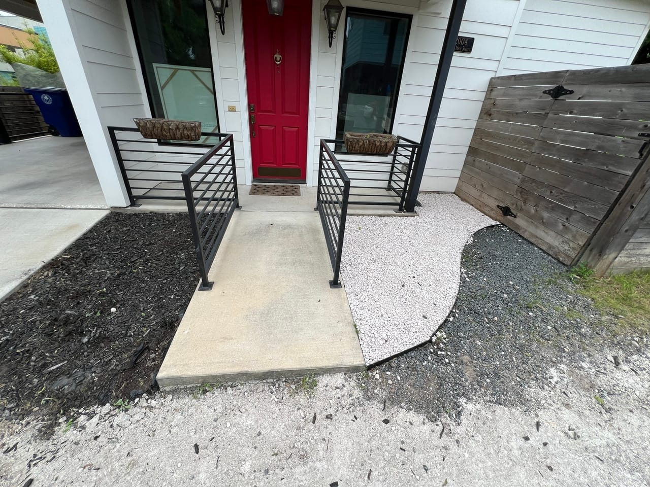 Clean walkway between gravel beds leading to a red front door in Leander, TX