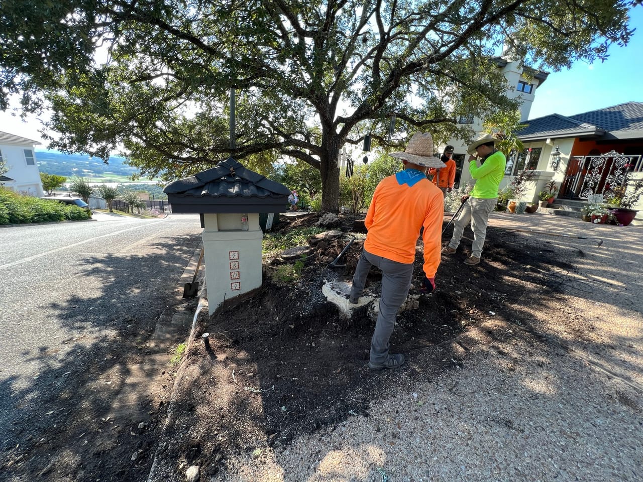Crew mulching a raised roadside planting bed beside a city street by Corral Bros in Central Texas
