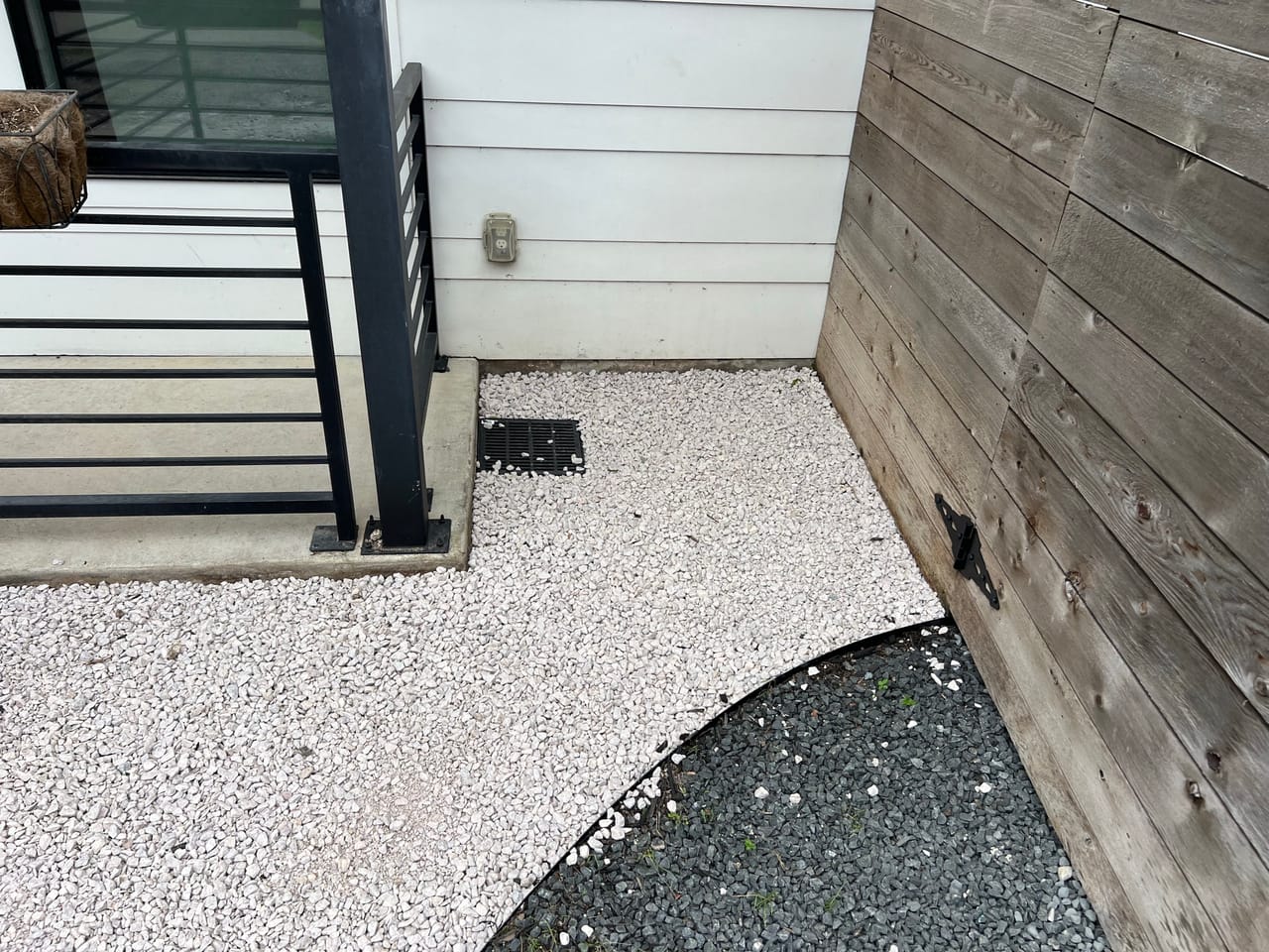 Curved black and white gravel beds meeting a fence and steps in Central Texas