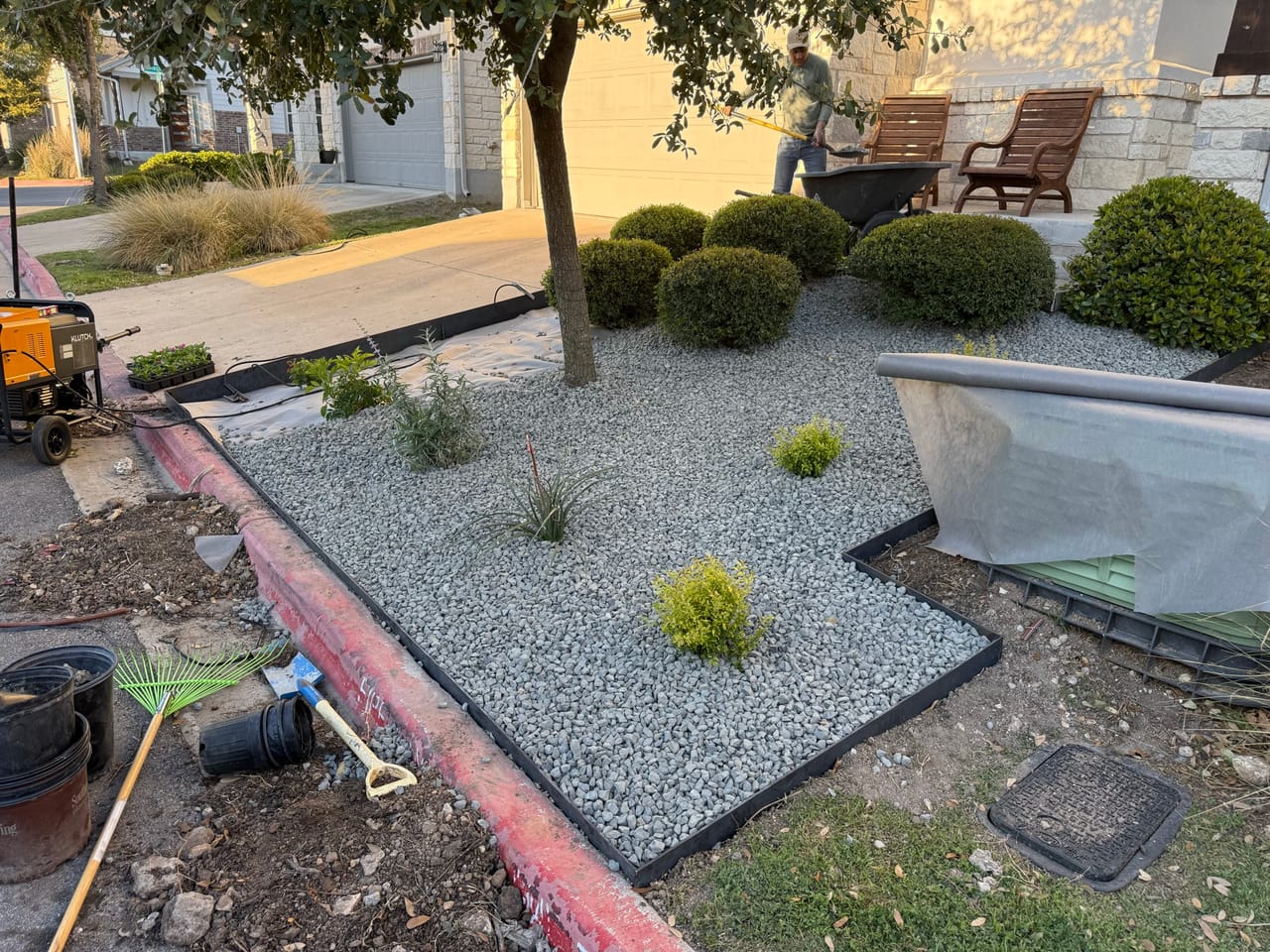 Front bed with white gravel, small shrubs and steel edging in progress by Corral Bros in Central Texas
