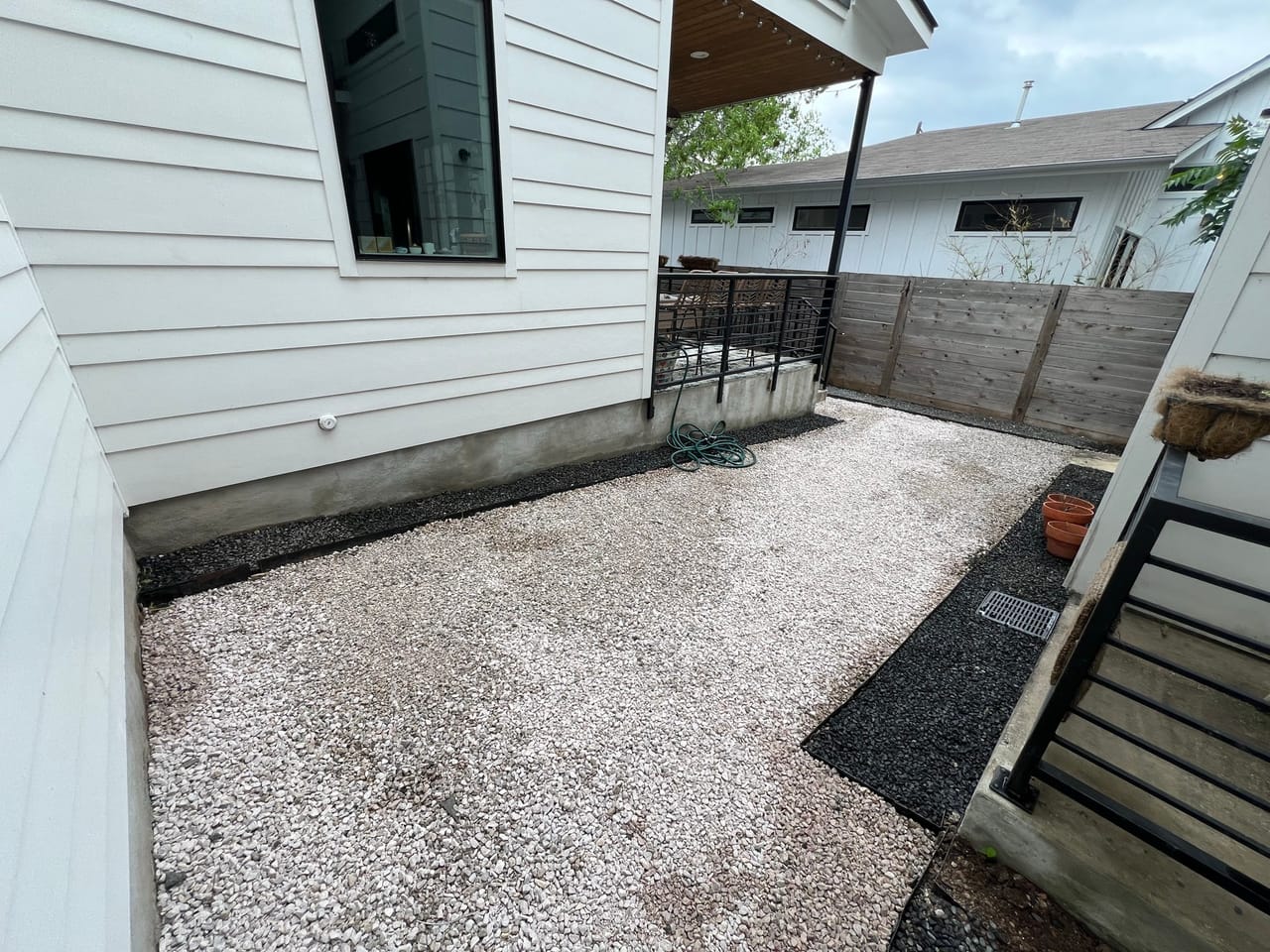 Gravel side yard beside a modern white house and fence by Corral Bros in Central Texas