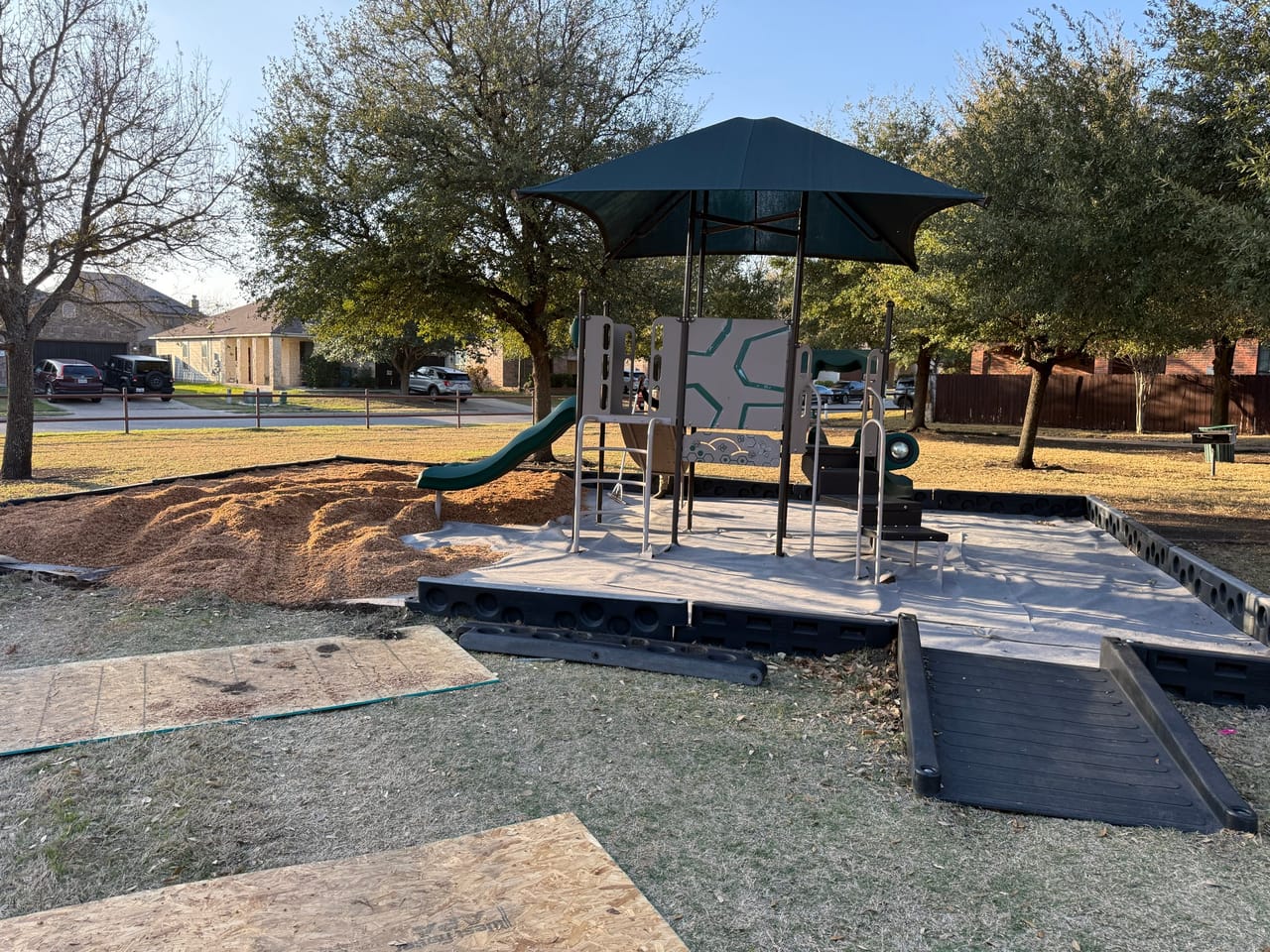 Playground with dumped mulch pile and rubber ramp panels staged by Corral Bros in Central Texas