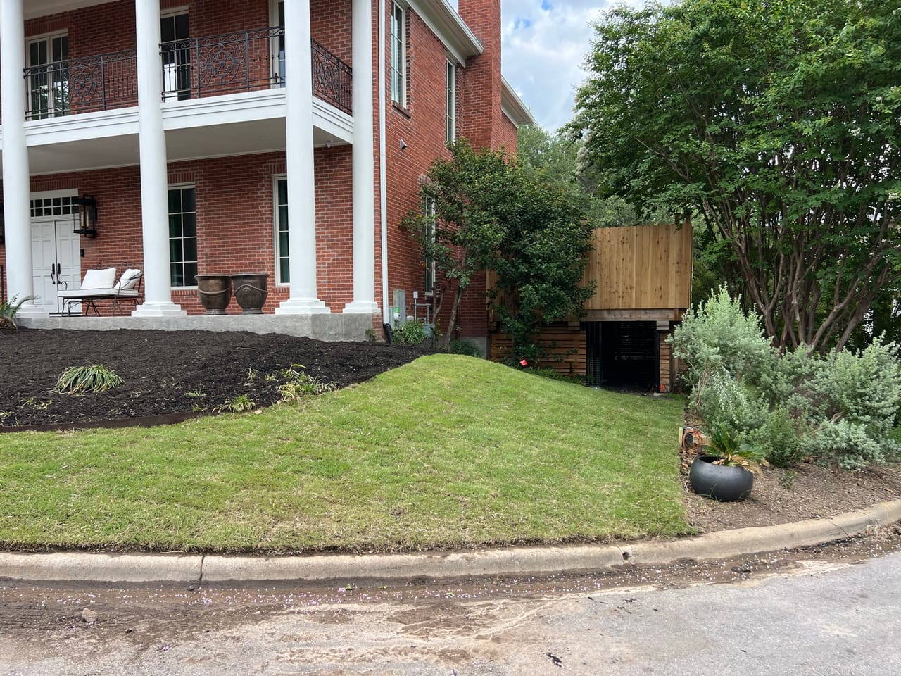 Side of brick building with mulched beds and trimmed shrubs in Central Texas