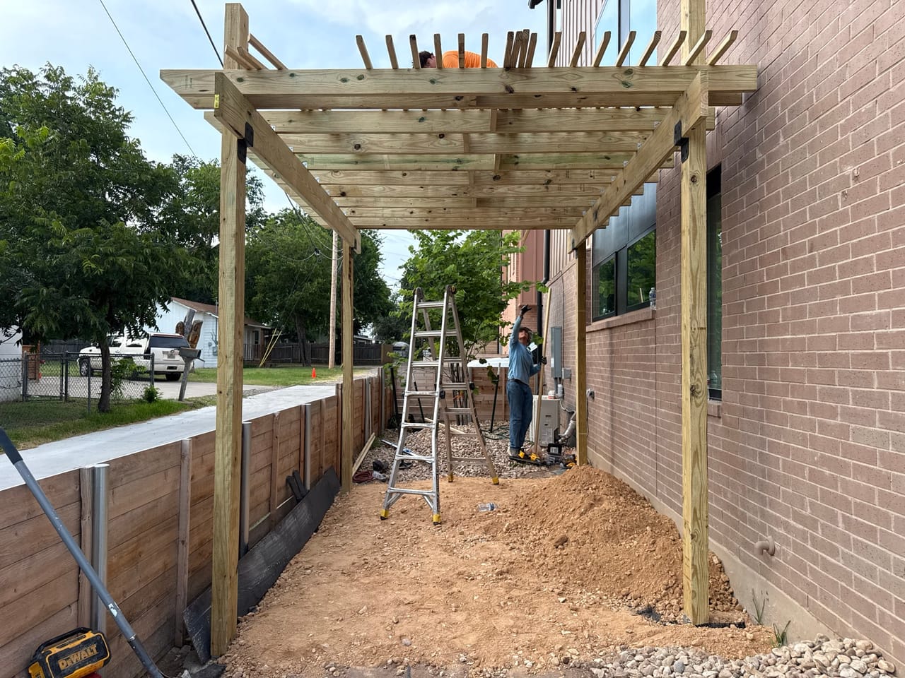 Completed pergola frame with slat top over a paver walkway in Pflugerville, TX