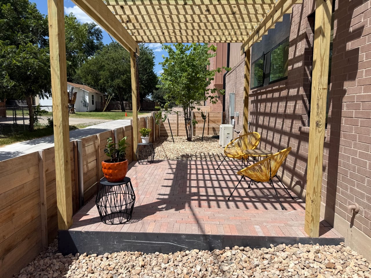 Finished pergola side yard with potted plants, swing and brick path in Kyle, TX