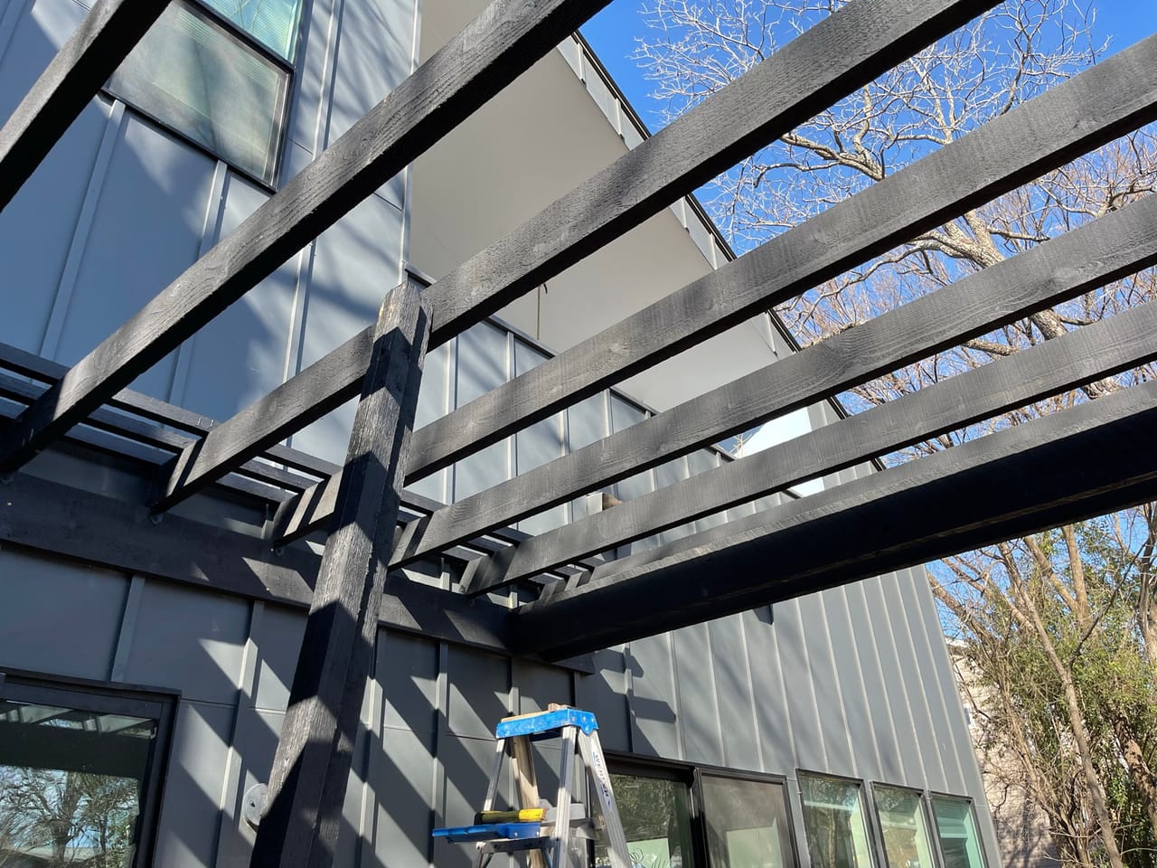 Steel pergola frame spanning a walkway at a modern commercial building in Pflugerville, TX