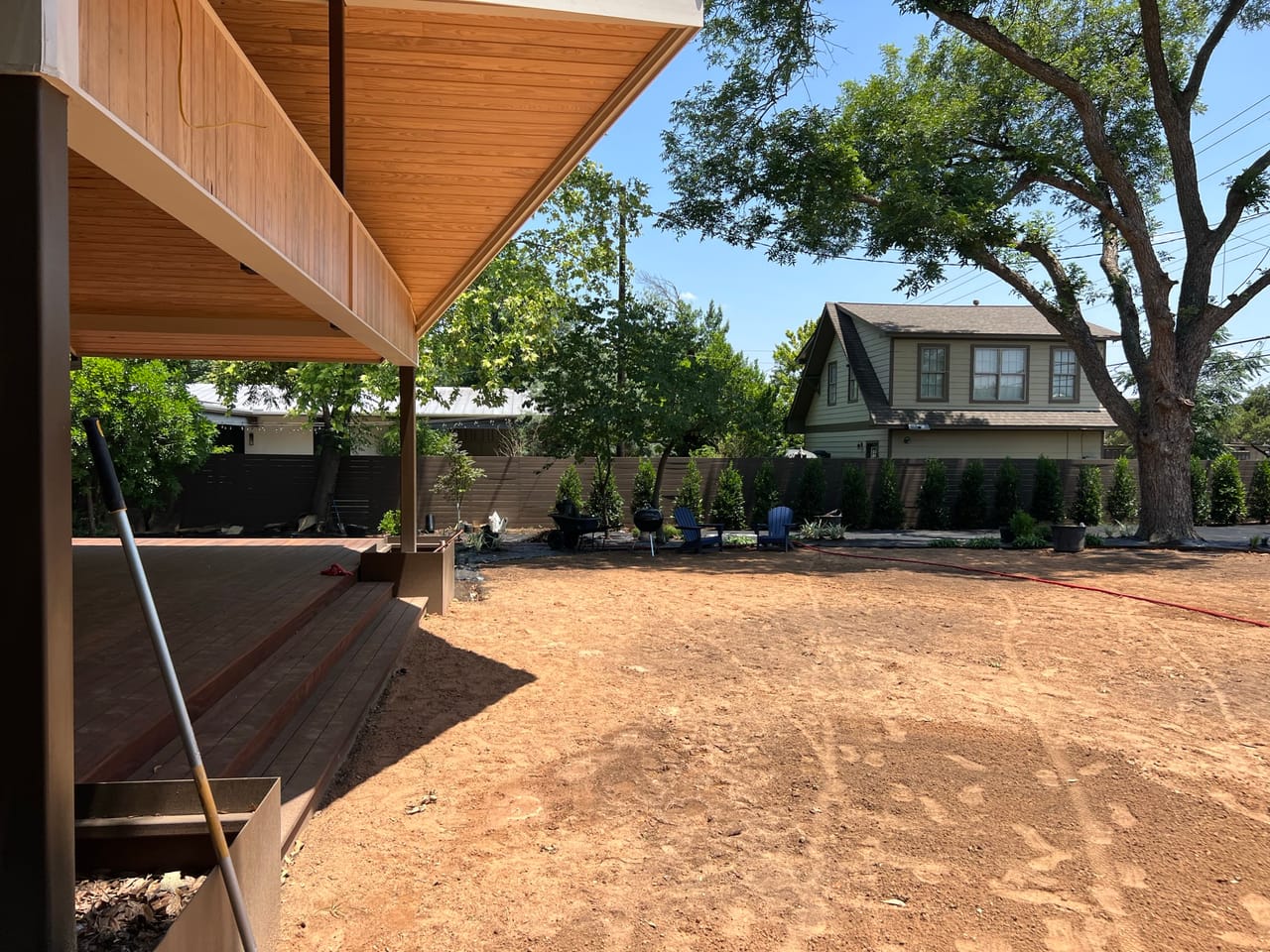 View from under a modern patio roof across a newly prepped yard in Leander, TX