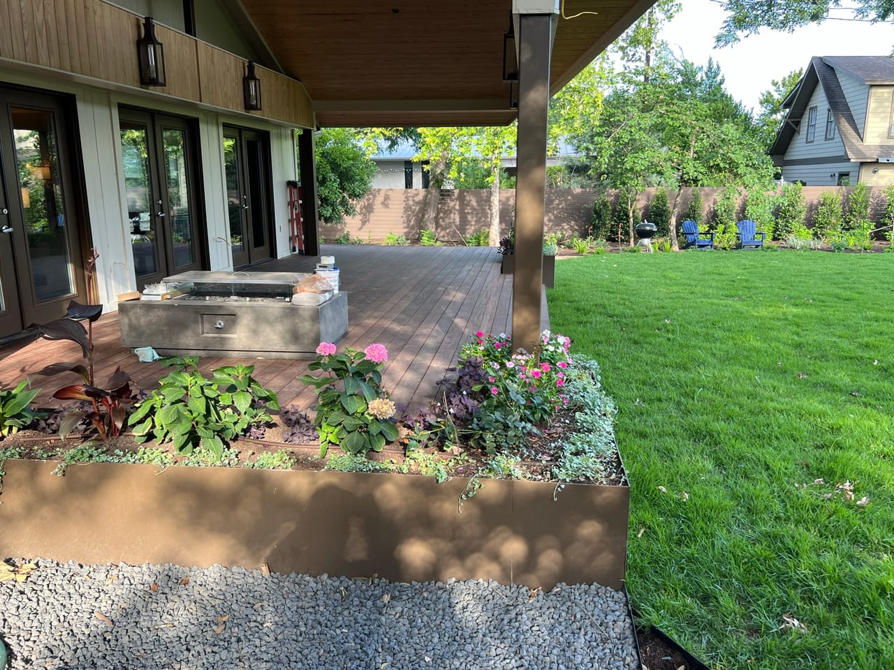 Full flower beds along a patio with a green lawn behind in Buda, TX