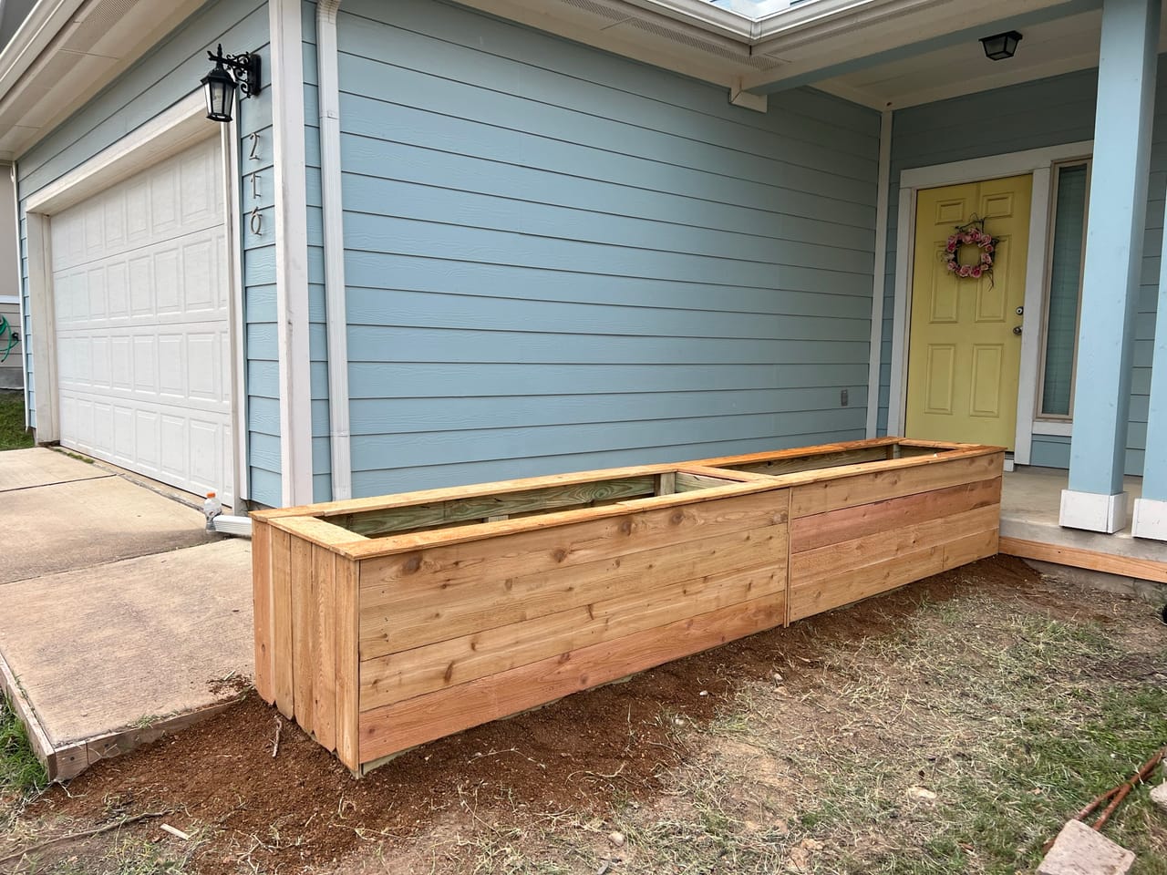 Long cedar raised bed built along a blue house near garage in Seguin, TX