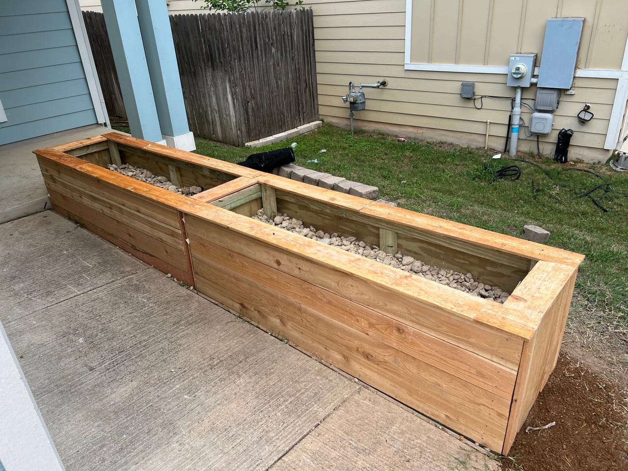 New cedar raised planter boxes along a fence with gravel border in Round Rock, TX