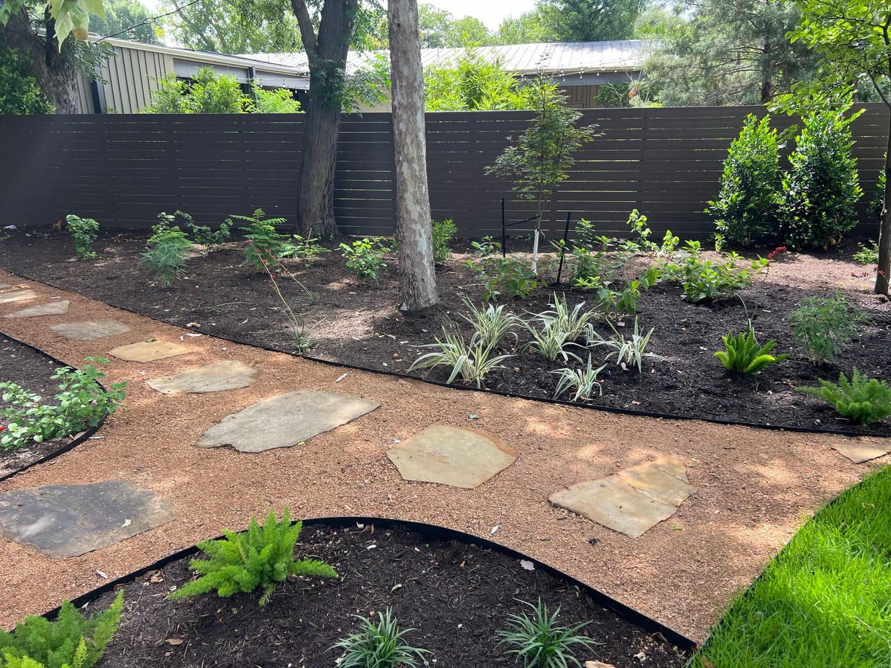 Stone stepping path with fresh plantings in dark mulch beds in Taylor, TX