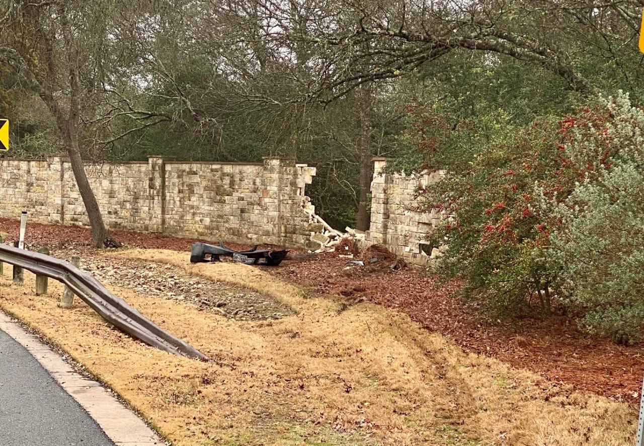 Broken section of a long stone wall with scattered debris below by Corral Bros in Central Texas