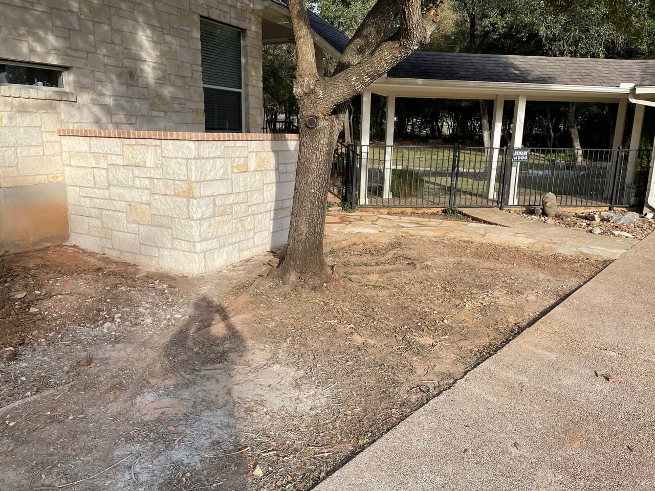 Capped stone wall completed along a graded dirt yard and fence by Corral Bros in Central Texas